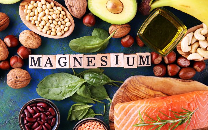 Products containing magnesium: bananas, almonds, avocado, nuts and spinach and eggs on table